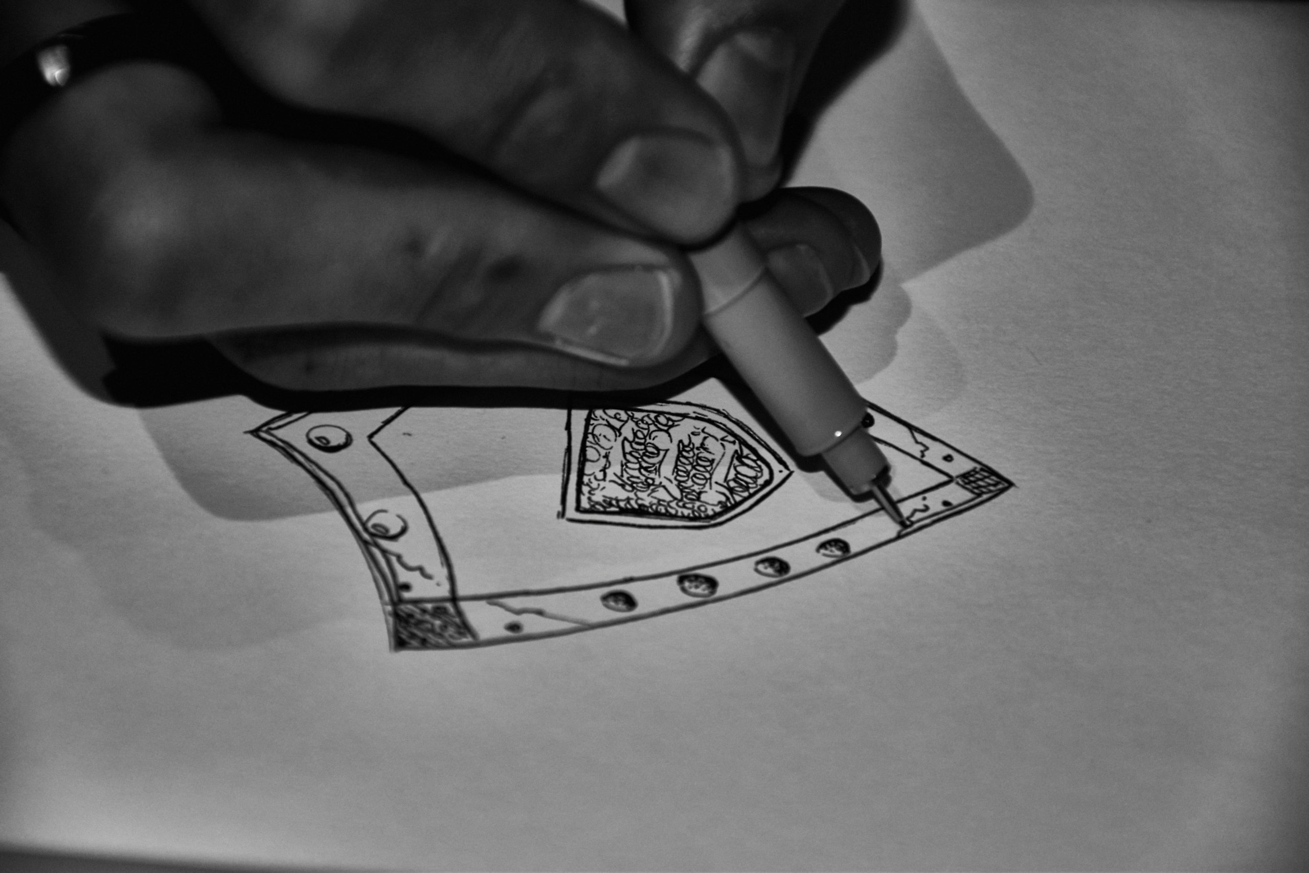 Artist drawing intricate design on paper with pen.